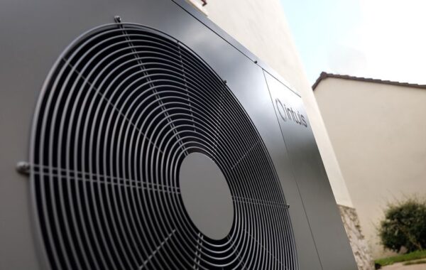 Ventilateur d'une pompe à chaleur Intuis HTi70 Gros plan sur le ventilateur et le logo Intuis d'une pompe à chaleur HTi70 installée contre un mur de maison